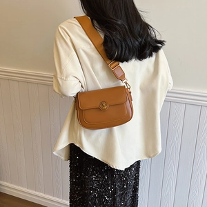 Brown vintage leather crossbody bag with lion head relief buckle and wide shoulder strap