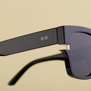 Gros plan sur les charnières dorées et les rivets de lunettes de soleil noires