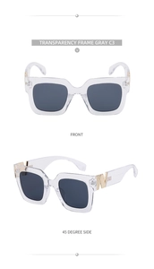 Detail view of transparent gray square sunglasses with gold metal logo on the temple