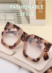Detailed view of tortoise shell square sunglasses on a cream leather folding case
