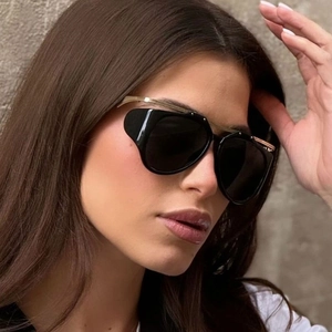 Close-up of cat-eye sunglasses with black frame and unique gold metal top bar detail