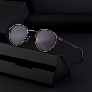 Retro punk round frame sunglasses with dark metal finish and black lenses on a leather case