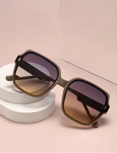 Detail of taupe matte square sunglasses with gradient lenses on a minimalist stone display