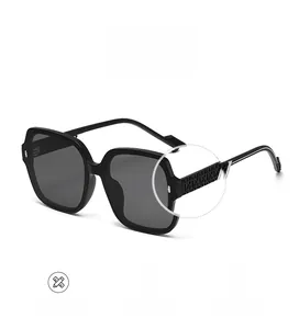 Close-up of black square sunglasses featuring embossed floral pattern and silver V logo
