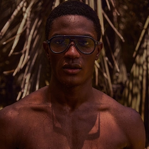 Retro pilot sunglasses for men with gold cross accents and dark lenses on a male model