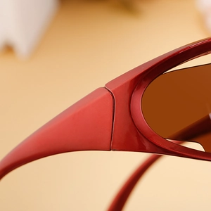 Detail of red sporty Y2K sunglasses with dark brown lenses and sleek streamlined design
