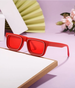 Détail de lunettes de soleil rectangulaires rouges avec des accents argentés et verres rouges