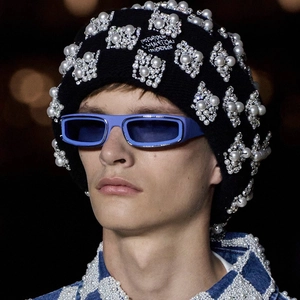 Close-up of black knit beanie with faux pearls, rhinestones and blue square sunglasses