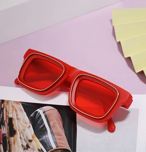 Détail de lunettes de soleil rouges à monture épaisse avec bordure en métal et verres rouges