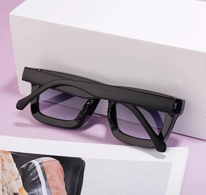 Détail de lunettes de soleil carrées noires avec verres dégradés violets sur support
