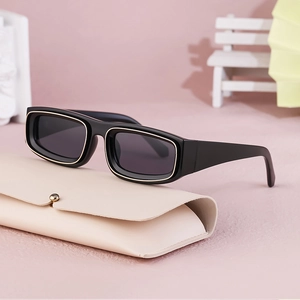 Detail shot of vintage black rectangle sunglasses with gold trim on a leather case