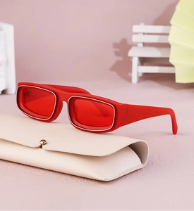 Detail of red rectangle sunglasses with silver trim and a beige leather folding case