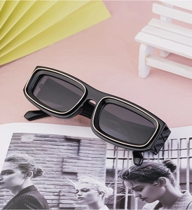 Detail view of retro small frame sunglasses with gold trim on black polished frames