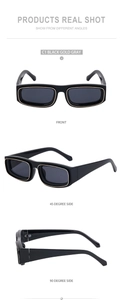 Detail view of square black sunglasses with gold metal trim and dark grey lenses