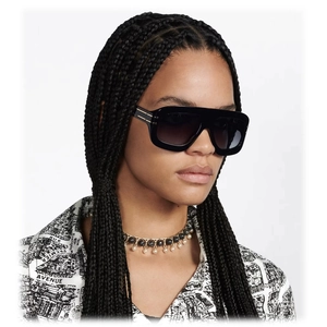 Detail of square black sunglasses featuring elegant gold bar accents on thick temple arms