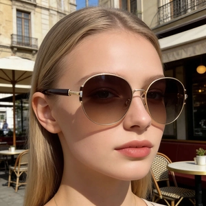 Close-up of a model wearing gold metal sunglasses with brown gradient lenses outdoors