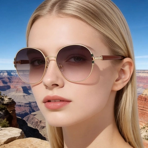 Detail view of round gold sunglasses with gradient lenses and classic striped hinges