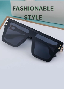 Close-up of black square sunglasses with gold rivet accents and polished metal hinges