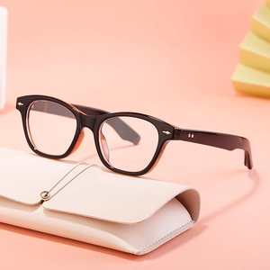 Retro black cat-eye sunglasses with orange lining on a leather case and yellow stand
