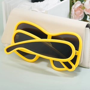 Detail view of bold yellow oversized sunglasses resting on a stylish beige leather clutch