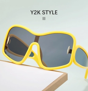 Detail view of yellow oversized Y2K sunglasses with dark lenses and gold metal accents