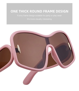 Detail of pink thick round frame sunglasses with brown lenses and metal rivets