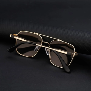 Detail einer hochwertigen quadratischen Sonnenbrille mit Goldrahmen und braunen Gläsern