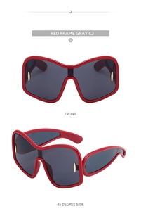 Detail view of red oversized sunglasses with grey one-piece lens and gold metal accents