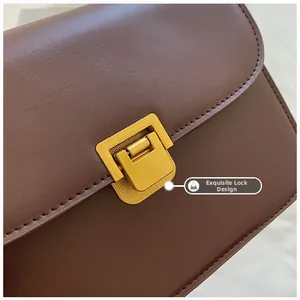 Detail of elegant gold rectangular twist lock on premium dark brown leather handbag