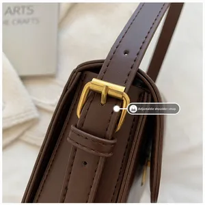 Detail of adjustable shoulder strap with vintage gold buckle on a brown leather bag