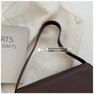 Detail showing smooth brown leather texture and slender shoulder strap of the square bag