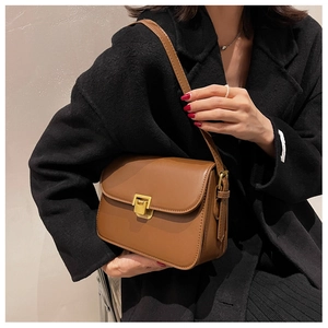 Brown vintage square shoulder bag with gold clasp shown on a model wearing a black coat