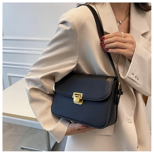 Classic black square shoulder bag with gold metal buckle worn with a white blazer