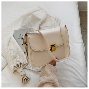 Detail of cream leather crossbody bag featuring gold square buckle and dual straps