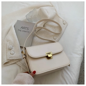Close-up of cream PU leather crossbody bag with matte gold square metal buckle detail