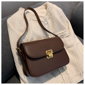 Detail of a deep chocolate faux leather flap bag with elegant gold metallic buckle hardware