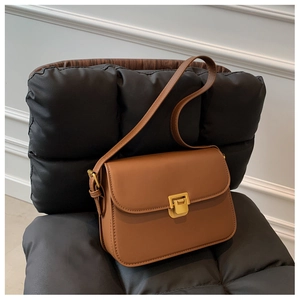 Detail view of a vintage brown leather crossbody bag with a square gold metal clasp