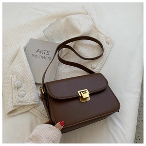 Close-up of a vintage brown leather crossbody bag with a gold metal snap button closure