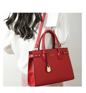 Dettaglio macro della borsa tote in pelle rossa con trama e rivetti dorati