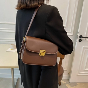 Elegant brown leather crossbody bag with golden square lock shown on female model