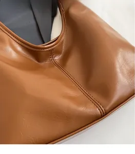 Gros plan sur la texture en cuir marron et les coutures soignées de ce sac seau élégant