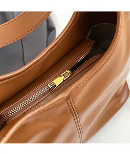Gros plan sur la fermeture éclair en métal doré du sac seau en cuir marron caramel