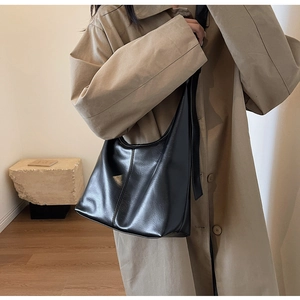 Détail d'un grand sac hobo noir montrant sa forme souple et sa texture en cuir lisse