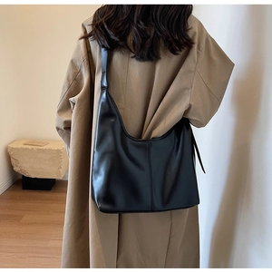 Détail d'un grand sac hobo noir en similicuir avec une large bandoulière sur modèle
