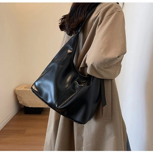 Vue détaillée du grand sac cabas en cuir noir brillant avec large bandoulière porté
