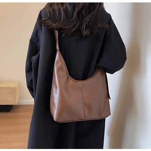 Détail d'un grand sac hobo marron montrant la texture du cuir de qualité et la couture centrale