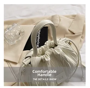 Detail view of white pleated bucket bag featuring comfortable handle and drawstring