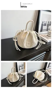 Detail view of a white pleated bucket bag with a drawstring closure and a top handle