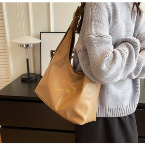 Gros plan sur la texture du cuir kaki lisse et la boucle en métal du sac hobo seau