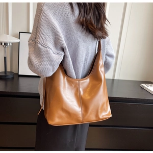 Grand sac hobo en cuir marron porté par un mannequin dans un décor au style minimaliste